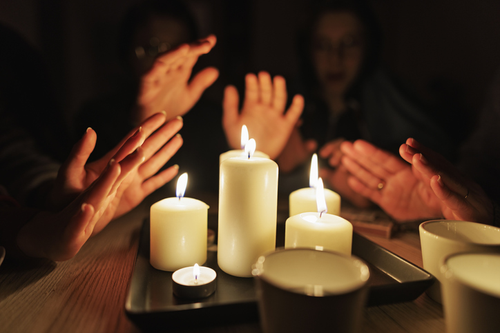 rodzina siedząca przy stole oświetlonym świecami